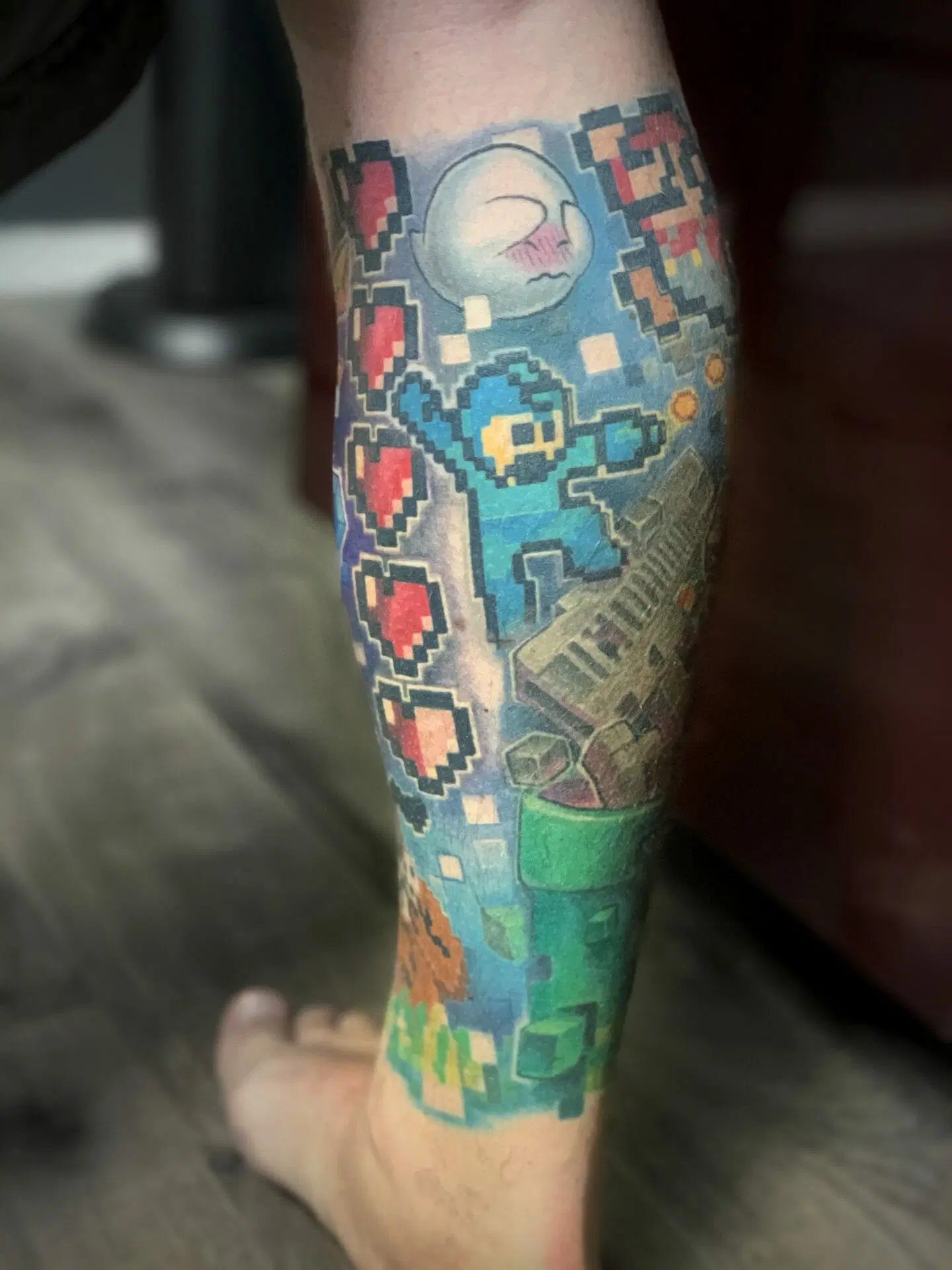 A man having his first tattoo experience with a nintendo tattoo on his leg.