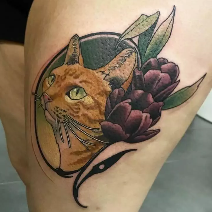 A floral cat tattoo displayed on a thigh.