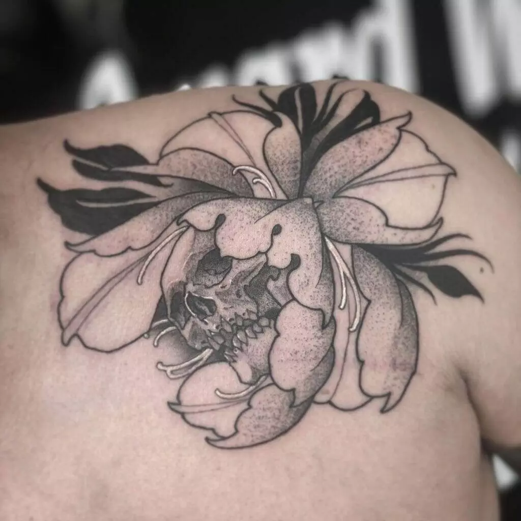 A black and white flower tattoo showcasing a man's shoulder in a tattoo artist's portfolio.