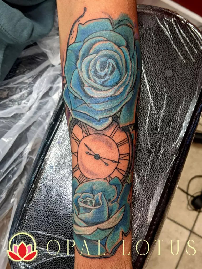 A tattoo featuring blue roses and a clock.